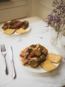 2 plates of instant pot ratatouille dish with pan-fried tofu on white table cloth and purple flowers