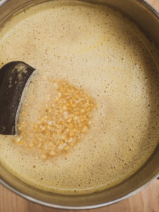 A spatula stiring oatmeal cooking in vegetable stock for the savory oatmeal recipe
