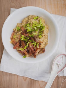 Sliced bacon with green onions on top of savory oatmeal for inspiration for savory oatmeal recipe