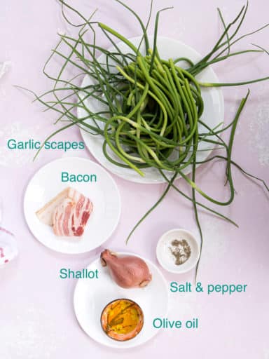 All the ingredients needed for sautéed garlic scapes on a purple background