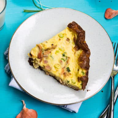 A slice of pink oyster mushroom quiche on a white plate