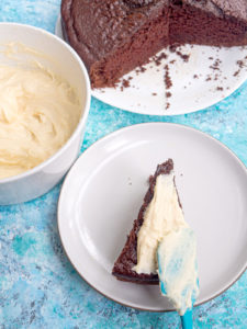 Frosting a slice of chocolate cake with cream cheese frosting
