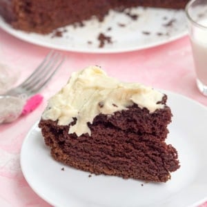 A slice of chocolate cake with cream cheese frosting on a white plate