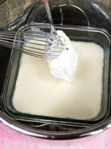 A spoon with yogurt next to a whisk