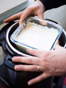 Alex's hands removing the glass container of crème fraîche from the Instant Pot