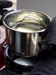 Hands with oven mitts lifting the inner pot out of the Instant Pot