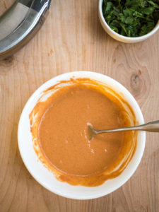 Mixed peanut butter, ketchup, and sriracha sauce with water in white bowl for Five Spice Tofu with Ketchup and Peanut Butter Sauce recipe