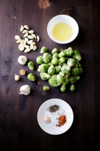 Overhead view of all ingredients for garlic brussels sprouts (salt, pepper, olive oil, brussels sprouts, etc). Recipe from garlicdelight.com.