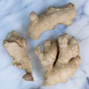 3 pieces of ginger root on white marble background