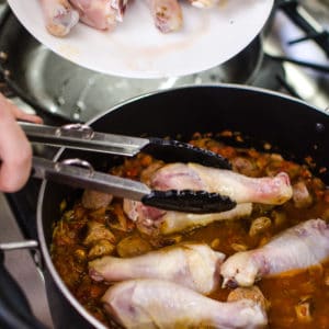 Shot of adding drumsticks to the pot. Jambalaya Recipe from garlicdelight.com.