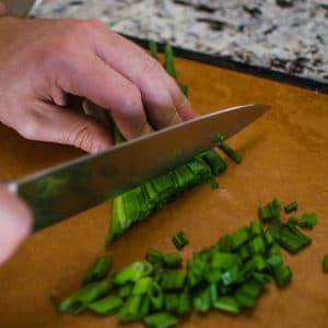 Close up shot of Alex chopping green onions. Jambalaya Recipe from garlicdelight.com.