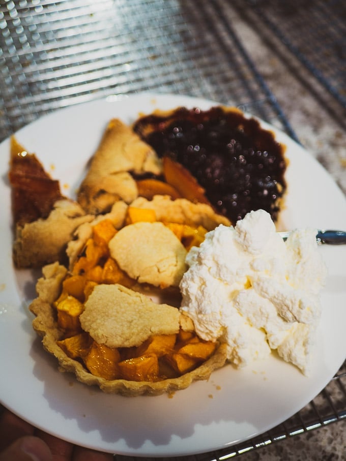 Cherry pie, mango pie, and 2 slices of peach galette with a generous amount of whipped cream