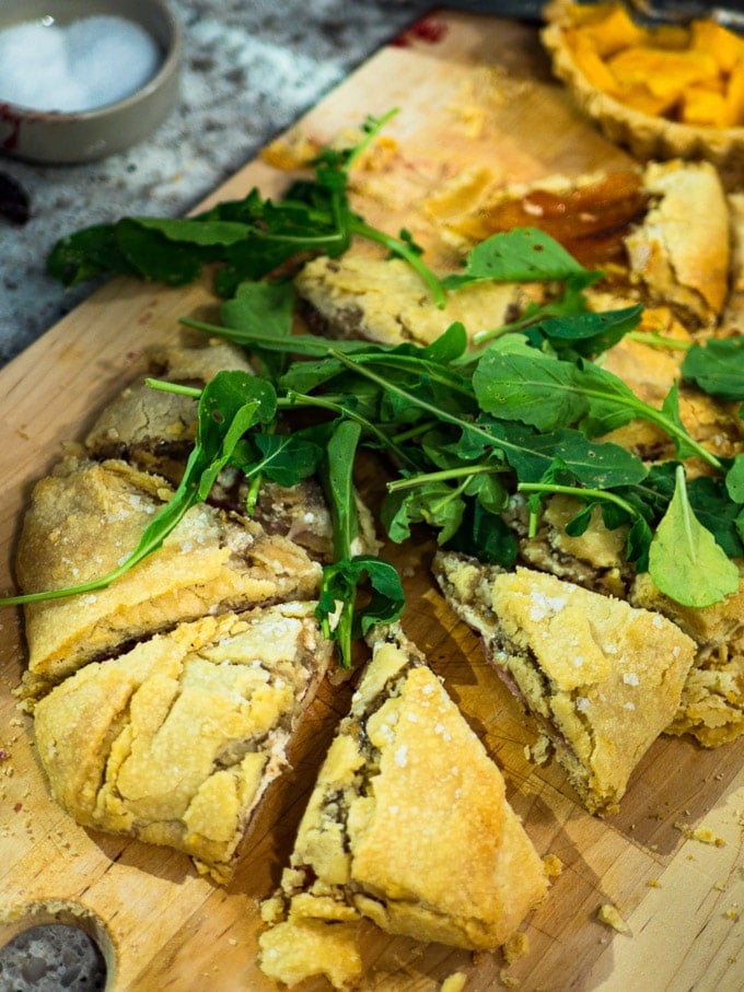 Sweaty Cat Pie with thinly sliced prosciutto at the base, smeared thickly with goat cheese, and drizzled with white wine chunky mushroom sauce on top, served with arugula and flaked salt