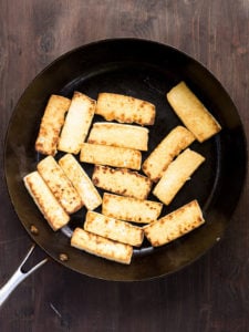 Pan-fried slices of super-firm tofu in a frying pan