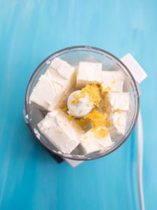 Blocks of cream cheese in a blender with lemon zest