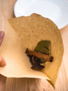 A coffee filter being filled with spices