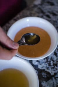 Close up shot of pouring apple cider vinegar sugar mix into spicy mayonnaise in a white bowl. Recipe from garlicdelight.com.
