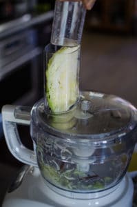 Close up shot of pushing a cabbage section into the food processor. Recipe from garlicdelight.com.