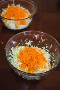 Long shot of shredded cabbage and carrots in bowls. Recipe from garlicdelight.com.